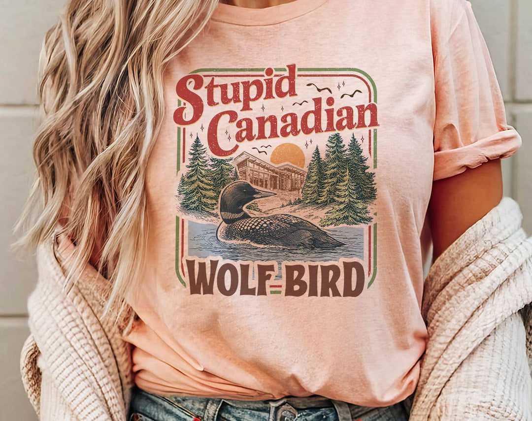 "Stupid Canadian Wolf Bird Heated Rivalry" design on a peach unisex t-shirt