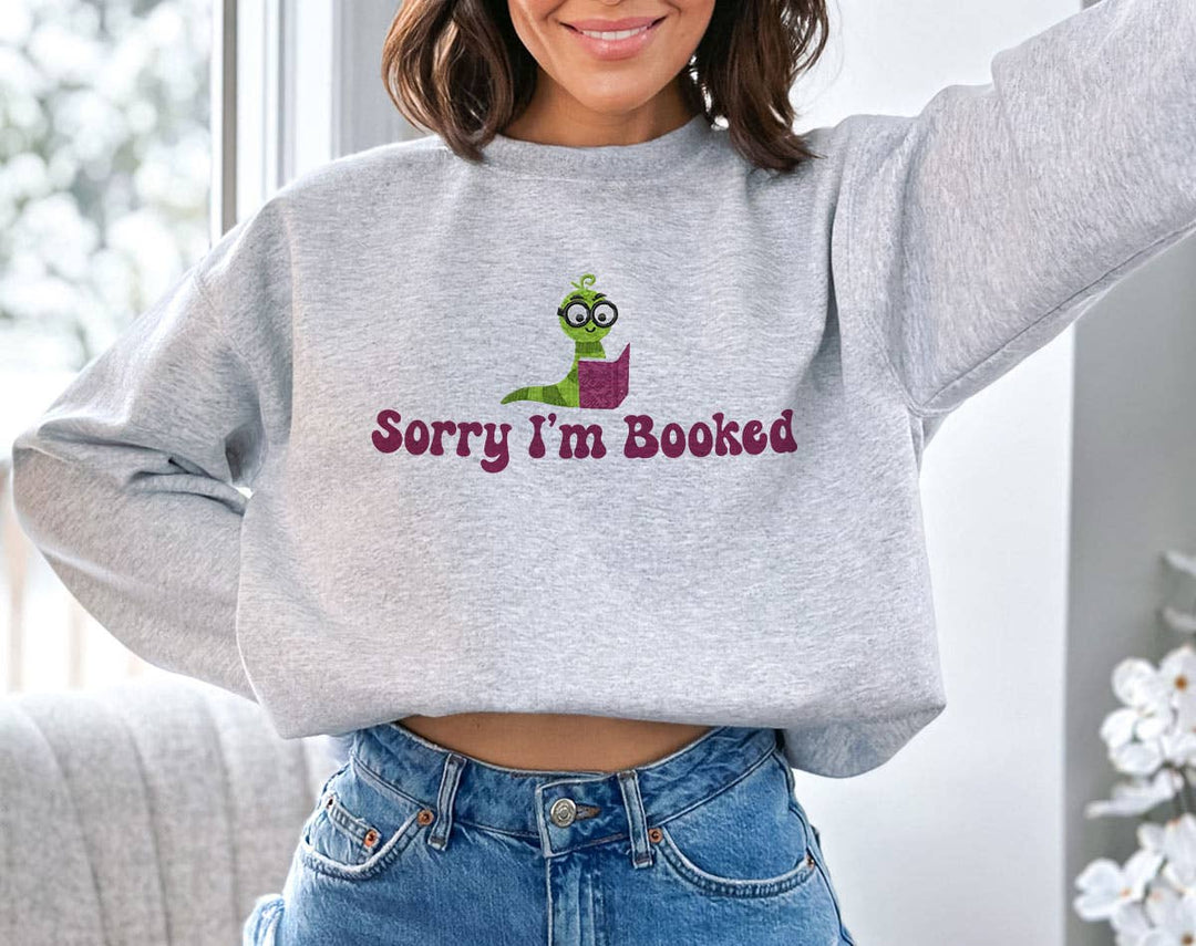 "Sorry I'm Booked" design on an ash gray unisex crewneck sweatshirt
