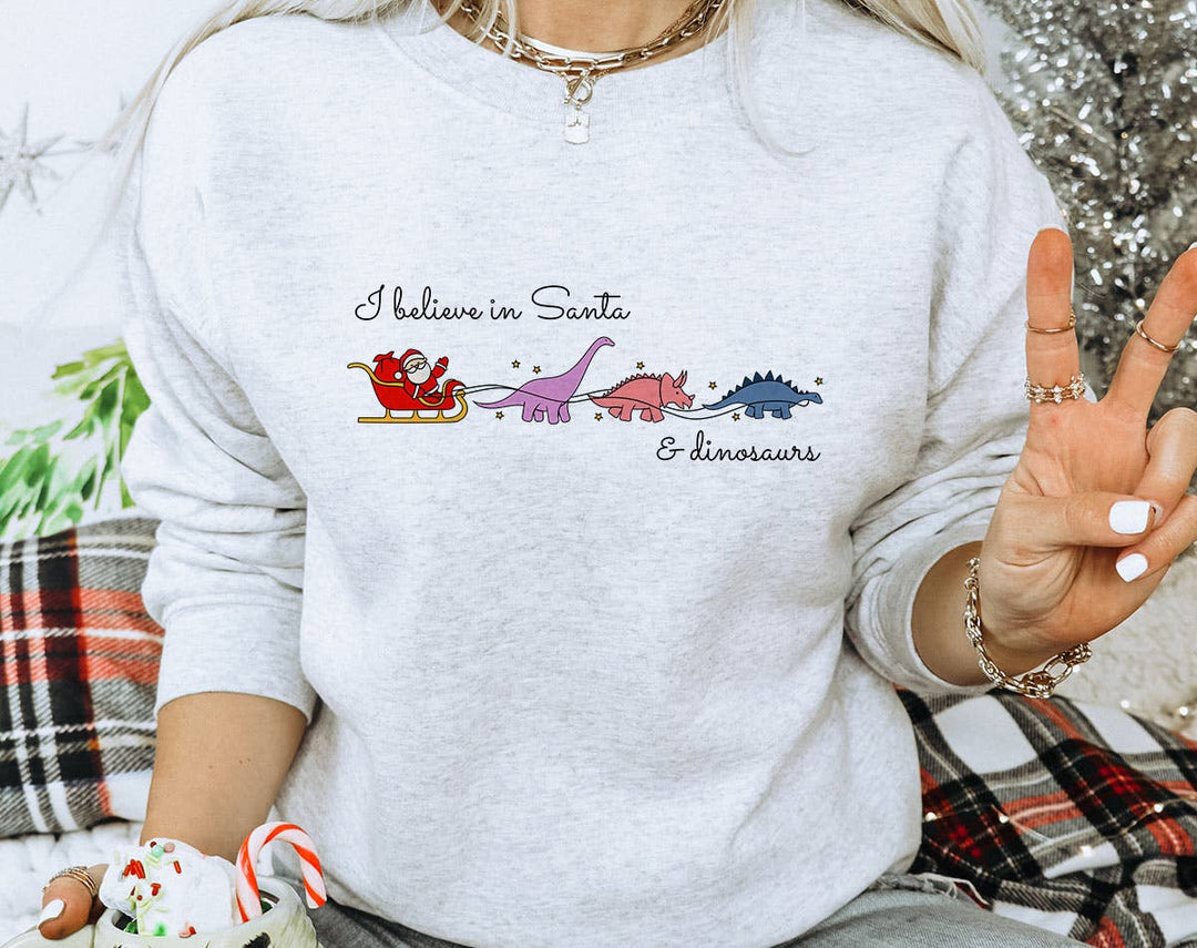 "I Believe In Santa & Dinosaurs" design on an ash gray unisex crewneck sweatshirt
