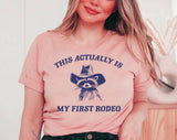 "My First Rodeo Raccoon" design on a peach unisex t-shirt