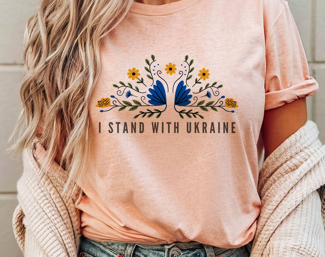 "I Stand With Ukraine Folk Flowers" design on a peach unisex t-shirt