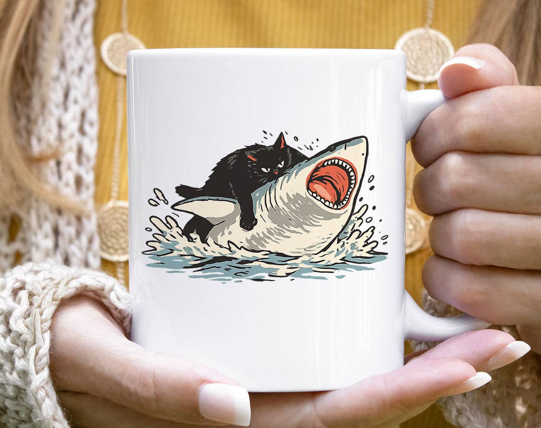 "Cat Riding Shark" design on a white ceramic coffee mug