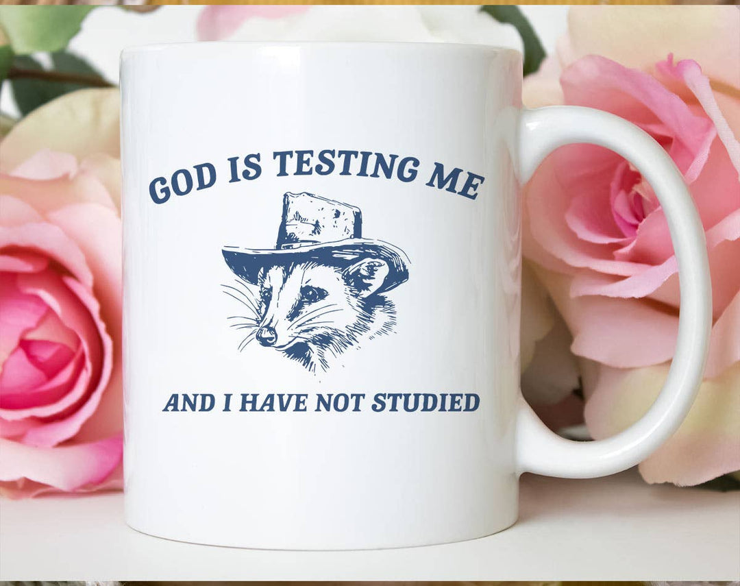 "God Is Testing Me Possum" design on a white ceramic coffee mug