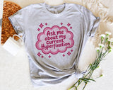"Ask Me About My Current Hyperfixation" design on a heather gray unisex t-shirt