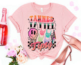 "Tanned Tatted Tipsy" design on a peach unisex t-shirt