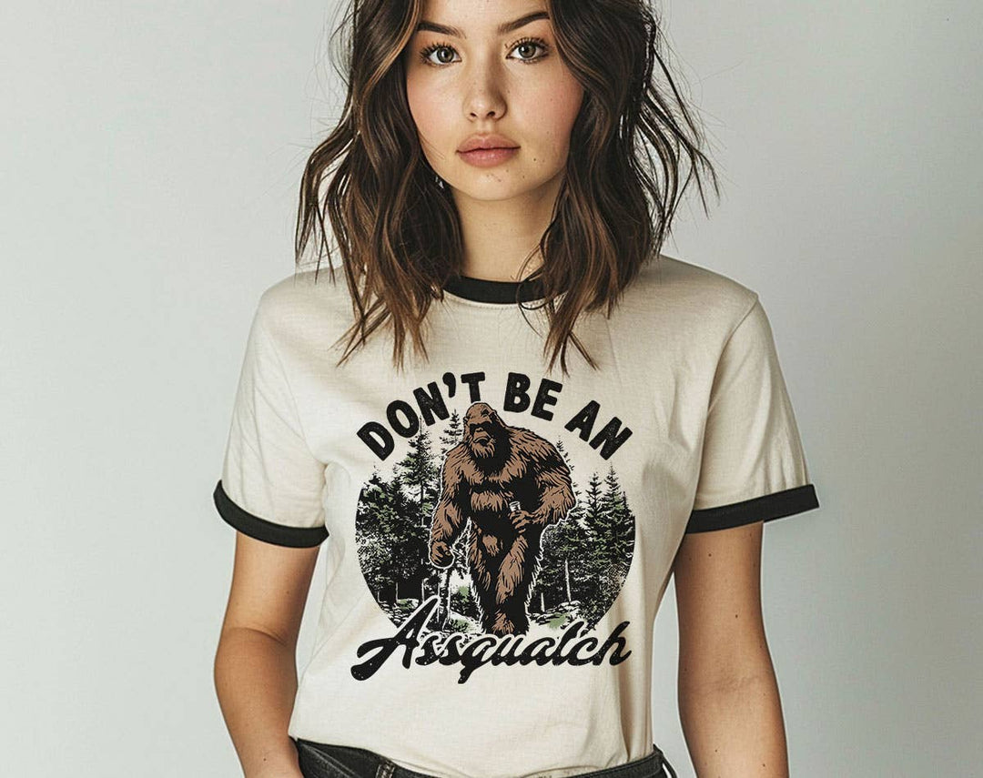 "Don't Be An Assquatch" design on a natural ringer t-shirt with black contrast trim