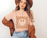 "Checkered Happy Face" design on a peach unisex t-shirt