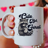 "Cute But Feral" design on a white ceramic coffee mug
