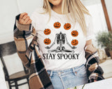 "Stay Spooky Skeleton Juggle" design on a white unisex t-shirt