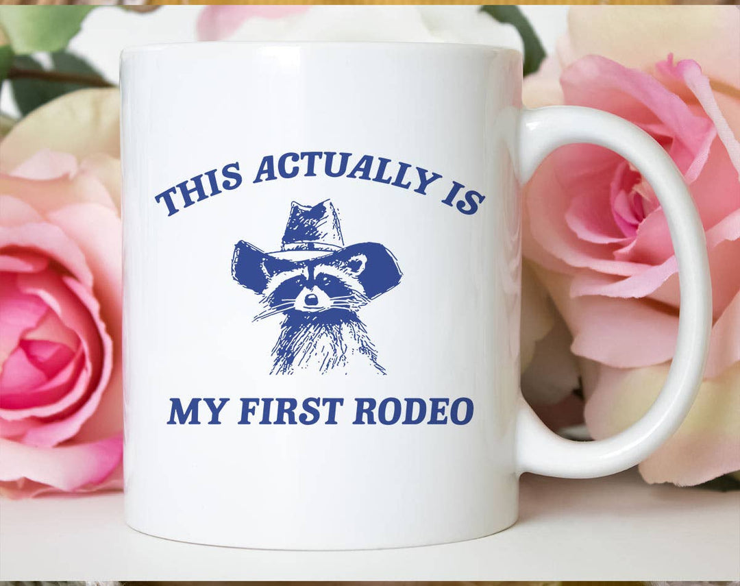 "My First Rodeo Raccoon" design on a white ceramic coffee mug