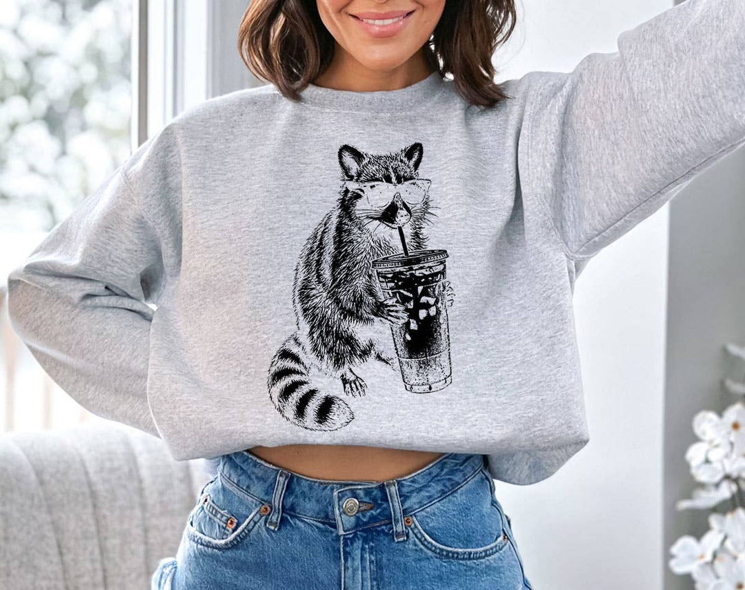 "Raccoon Drinking Iced Coffee" design on an ash gray unisex crewneck sweatshirt
