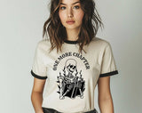 "One More Chapter Skeleton" design on a natural ringer t-shirt with black contrast trim