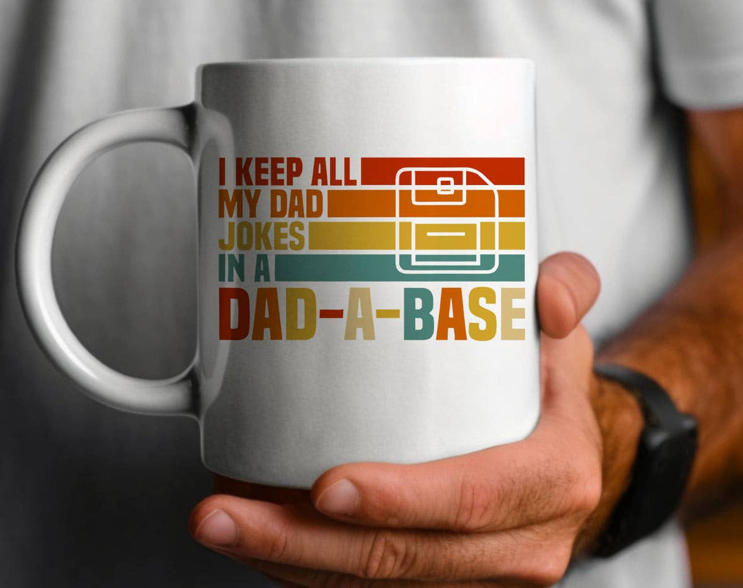 "I Keep All My Jokes In A Dad A Base Fathers Day" design on a white ceramic coffee mug