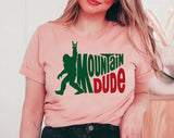 "Mountain Dude Bigfoot" design on a peach unisex t-shirt