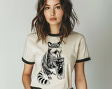 "Raccoon Drinking Iced Coffee" design on a natural ringer t-shirt with black contrast trim