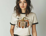 "Fourth Wing Pumpkin Book" design on a natural ringer t-shirt with black contrast trim
