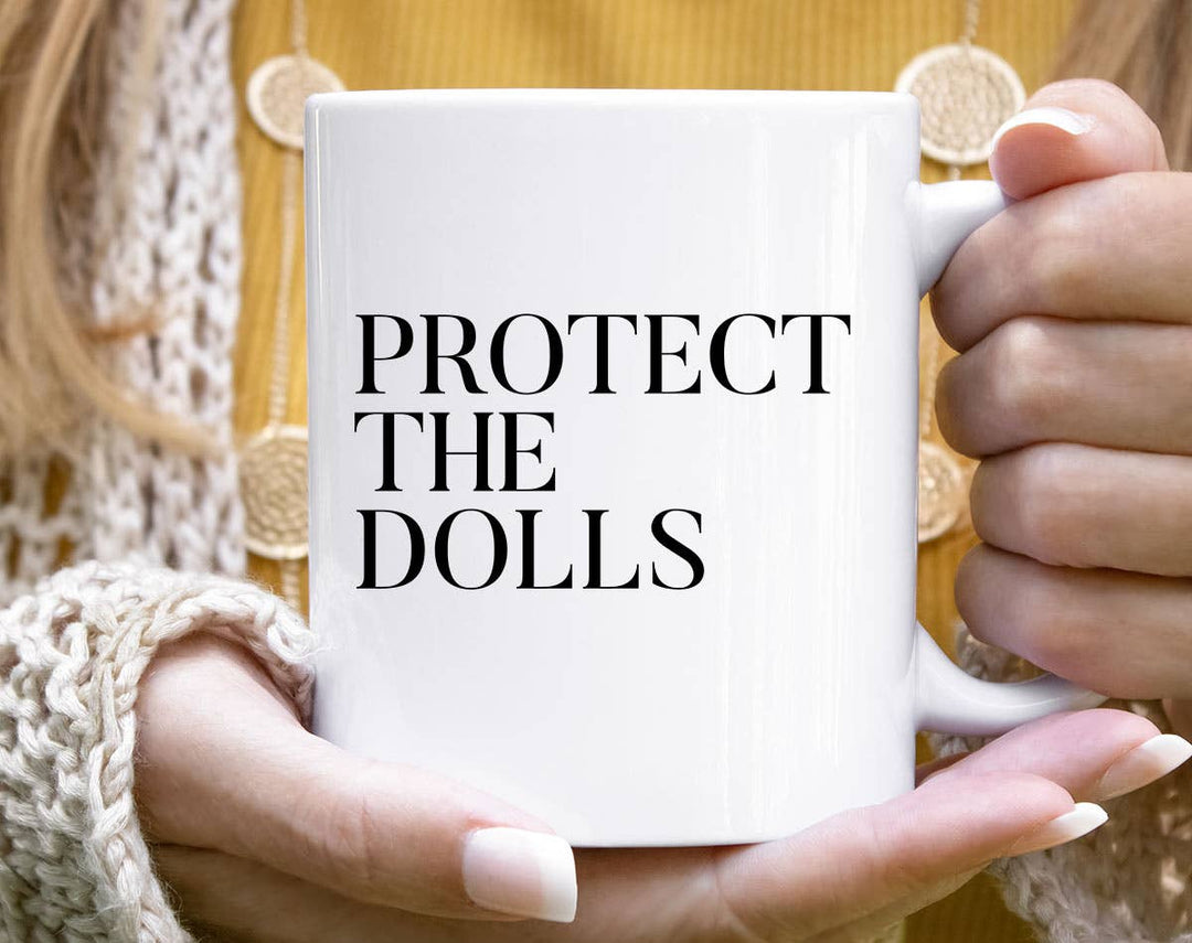 "Protect The Dolls" design on a white ceramic coffee mug