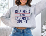 "Reading Is My Favorite Sport" design on an ash gray unisex crewneck sweatshirt