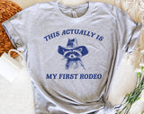 "My First Rodeo Raccoon" design on a heather gray unisex t-shirt
