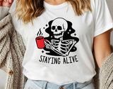 "Staying Alive Coffee Skeleton" design on a white unisex t-shirt
