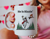 "He Is Rizzen" design on a white ceramic coffee mug