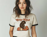 "Stay Kind Baby Punch Monkey" design on a natural ringer t-shirt with black contrast trim