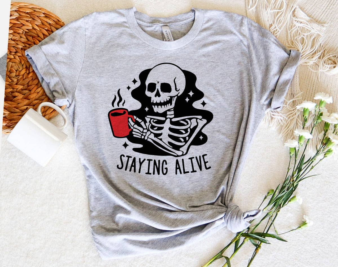 "Staying Alive Coffee Skeleton" design on a heather gray unisex t-shirt