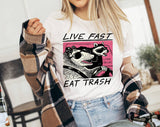 "Live Fast Eat Trash Raccoon" design on a white unisex t-shirt