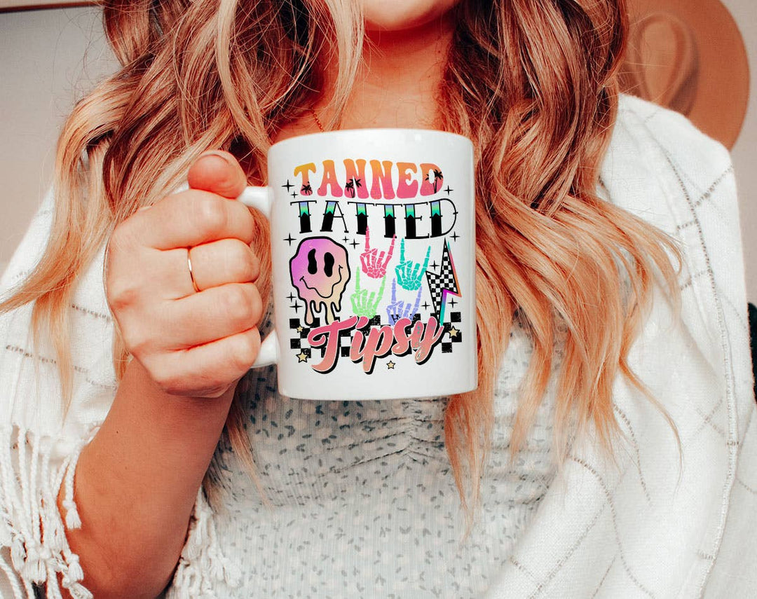 "Tanned Tatted Tipsy" design on a white ceramic coffee mug