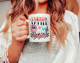 "Tanned Tatted Tipsy" design on a white ceramic coffee mug