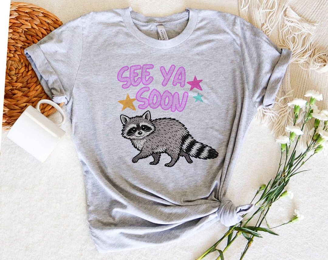 "See You Soon Raccoon" design on a heather gray unisex t-shirt