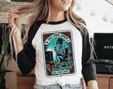 "True Crime Junkie Tarot" design on a white baseball raglan tee with black sleeves