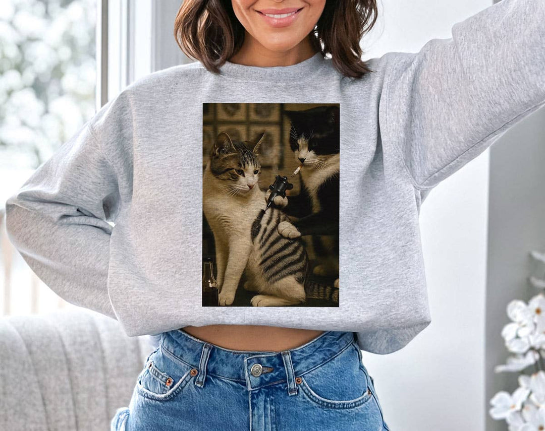 "Cat Getting Tattoo" design on an ash gray unisex crewneck sweatshirt