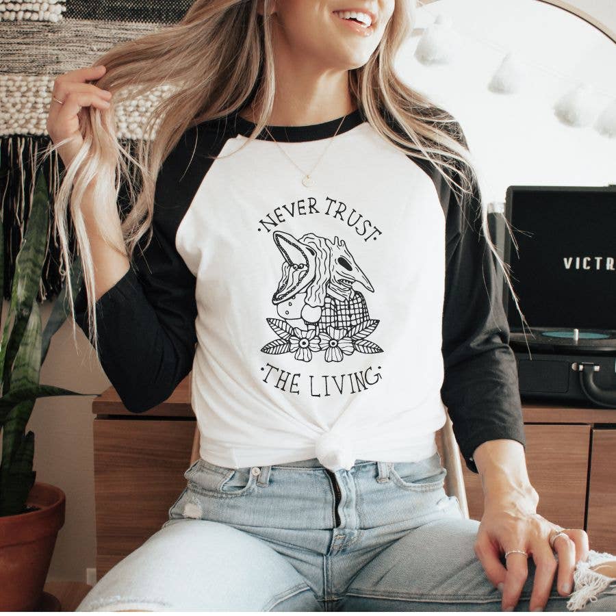 "Never Trust The Living" design on a white baseball raglan tee with black sleeves