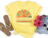 "Sunkissed Rainbow" design on a pale yellow unisex t-shirt