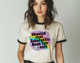 "Chasing That Scholastic Book Fair High" design on a natural ringer t-shirt with black contrast trim