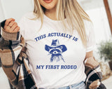 "My First Rodeo Raccoon" design on a white unisex t-shirt