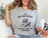 "I Bake Bread & Don't Trust The Government Raccoon" design on a heather gray unisex t-shirt