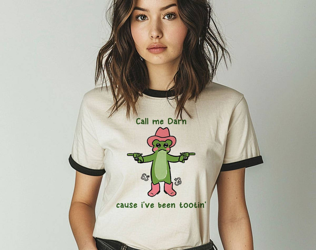 "Call Me Darn Cause I've Been Tootin" design on a natural ringer t-shirt with black contrast trim