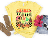 "Tanned Tatted Tipsy" design on a pale yellow unisex t-shirt
