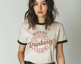 "Warning The Girls Are Drinking Again" design on a natural ringer t-shirt with black contrast trim