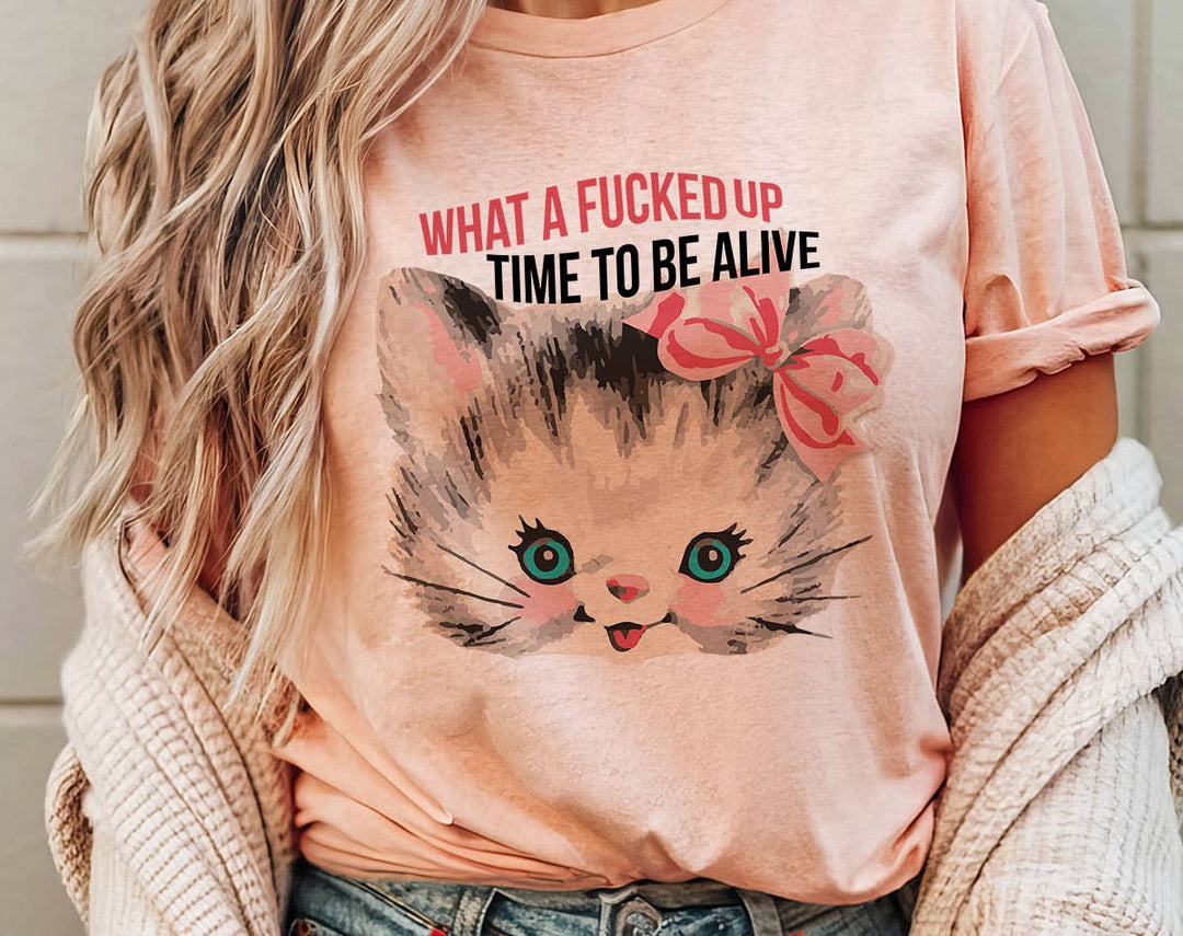 "What A F*cked Time To Be Alive Kitten" design on a peach unisex t-shirt
