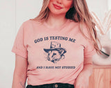 "God Is Testing Me Possum" design on a peach unisex t-shirt