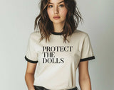 "Protect The Dolls Trans Rights" design on a natural ringer t-shirt with black contrast trim