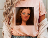 "Disgusted Doll Face Meme" design on a peach unisex t-shirt