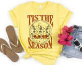 "Tis The Season Dancing Skeleton" design on a pale yellow unisex t-shirt