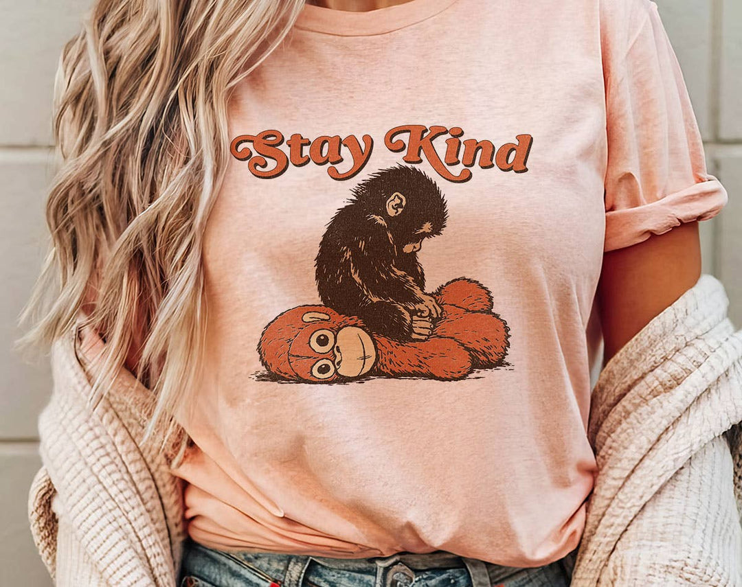 "Stay Kind Baby Punch Monkey" design on a peach unisex t-shirt